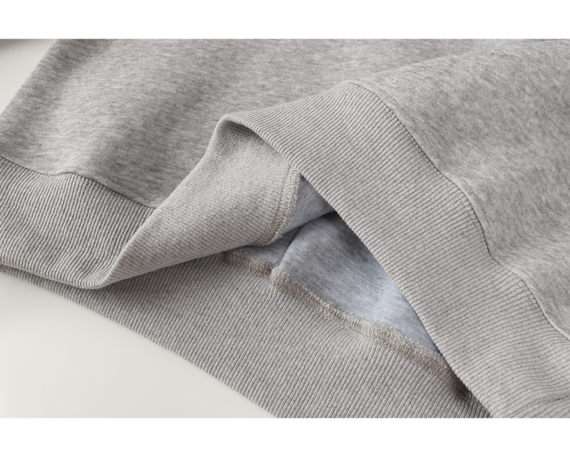 Close-up of hoodie hem and ribbed waistband seam in light gray