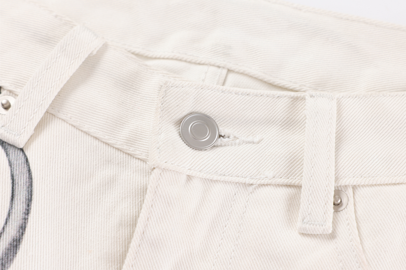 Close-up of cream jeans waistband with button, belt loop, and fine twill texture