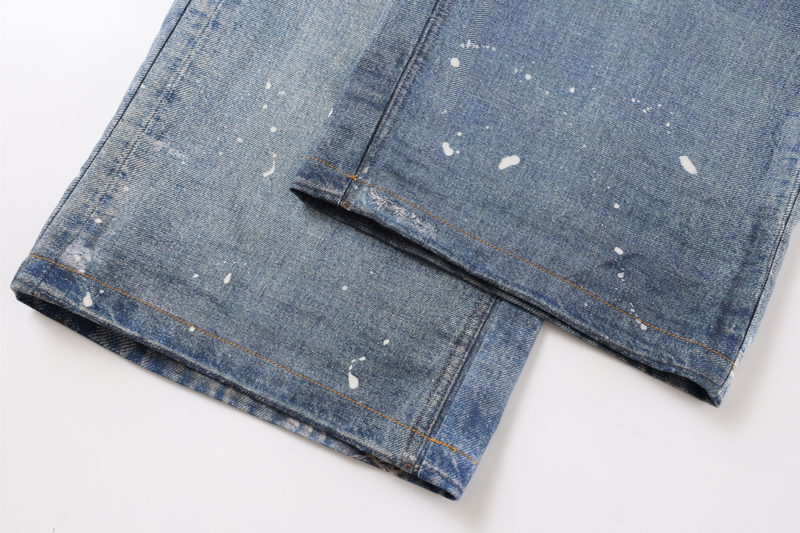 Bottom hems of wide-leg blue jeans with white paint speckles