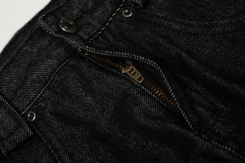 Close-up of black denim front zipper and fly stitching with metal zipper pull