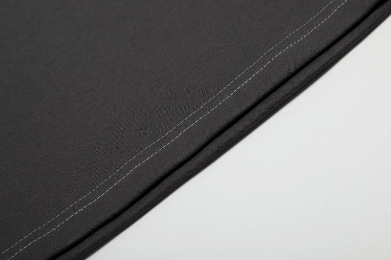 Close-up of black cotton tee fabric with contrast double stitching along the hem