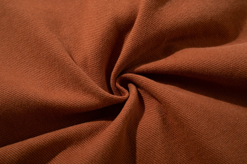 Close-up of rust brown cotton twill fabric with soft folded texture