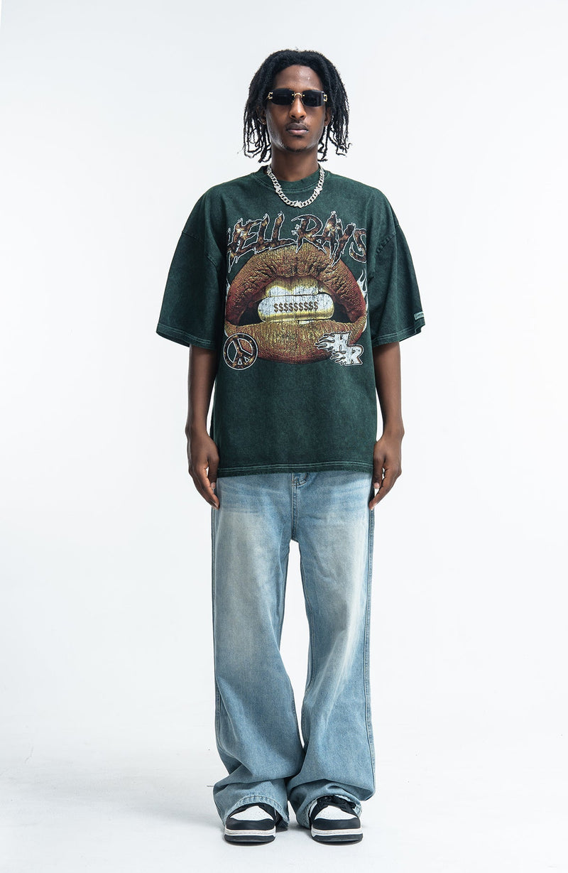 Model wearing a vintage washed dark green graphic tee with Hellrays lips print, loose faded jeans, and black sneakers