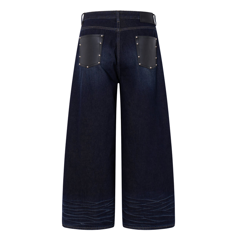 Back view of deep indigo wide-leg jeans with black leather patch pockets and a branded waistband patch