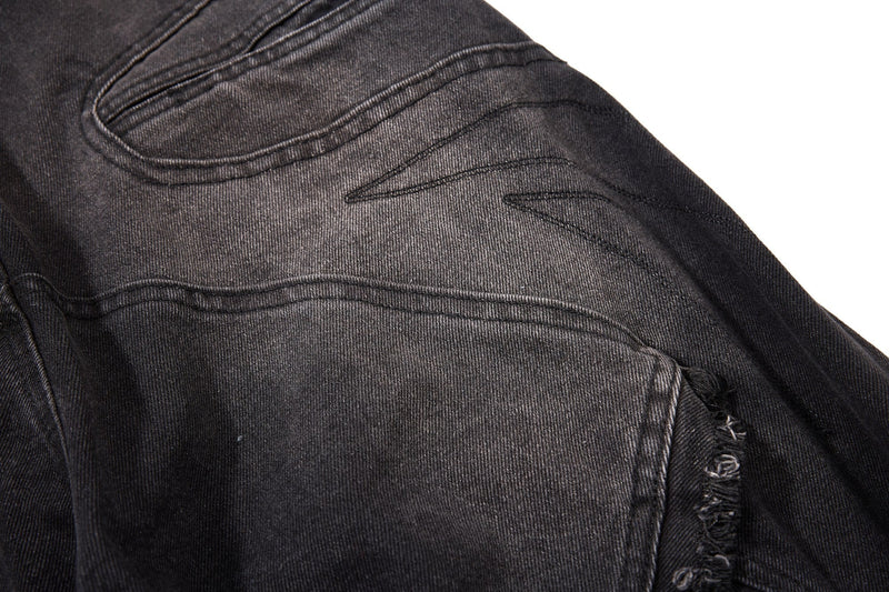 Close-up of black denim seat panel with curved seam stitching and worn fade