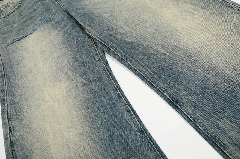 Close-up of faded blue denim legs with heavy wash marks and wide-leg cut
