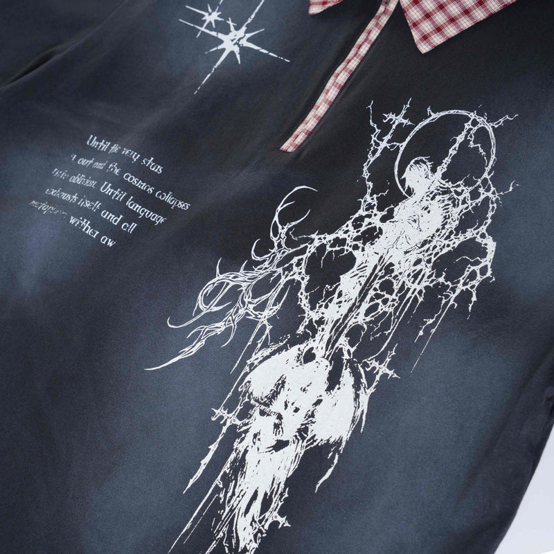 Black oversized polo with white cosmic graphic print, distressed text details, and red plaid collar trim