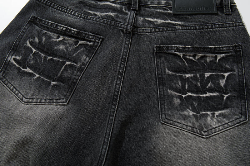 Close-up of the back pockets on black wide-leg jeans with cracked wash detailing