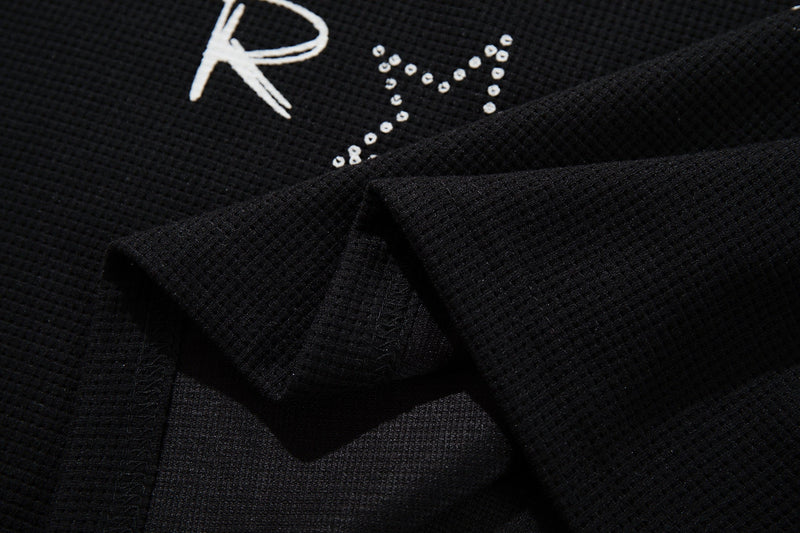 Close-up of black cotton graphic tee with white punk-style lettering and studded design detail