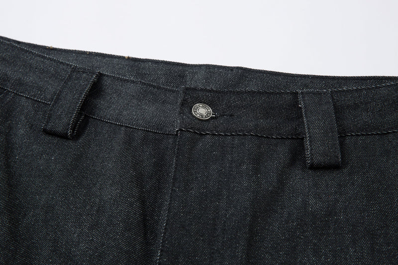 Close-up of the front waistband button and dark denim texture on pleated pants
