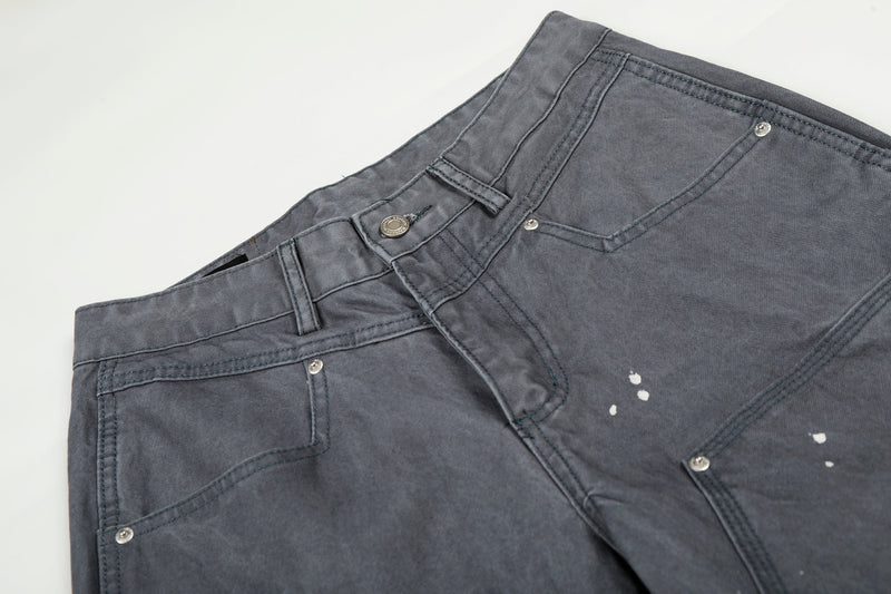 Close-up of gray jeans waistband and front pocket details with button fly and paint splatter marks