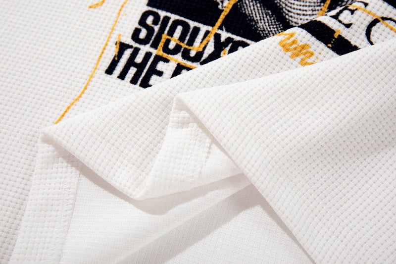 Close-up of folded white ringer T-shirt fabric with vintage alt-music graphic in black and gold print