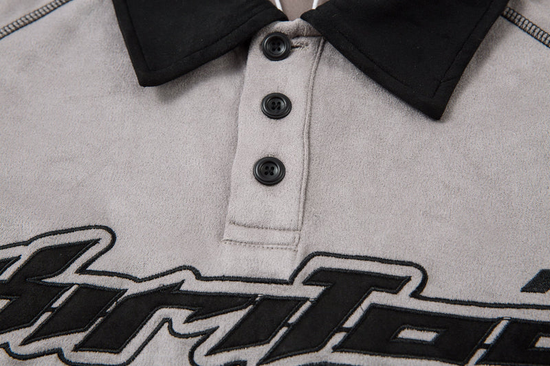 Close-up of button placket and black collar on the light gray polo shirt front