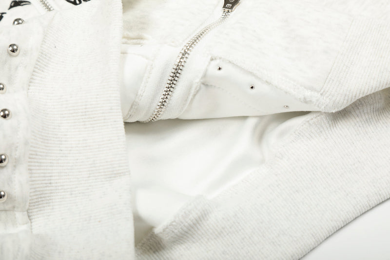 Close-up of white hoodie zipper, ribbed sleeve and studded front panel