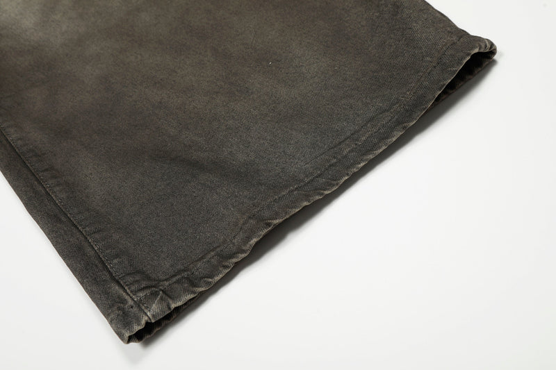 Close-up of hem on faded black wide-leg denim pants with visible stitching