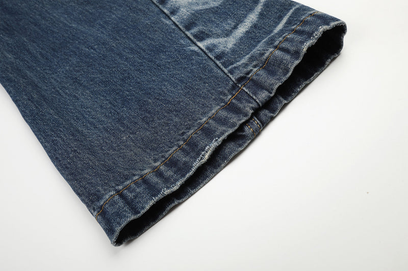 Close-up of hem on faded blue jeans with raw-edged cuff and stitching