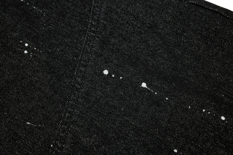 Close-up of black denim with white paint splatter on the leg