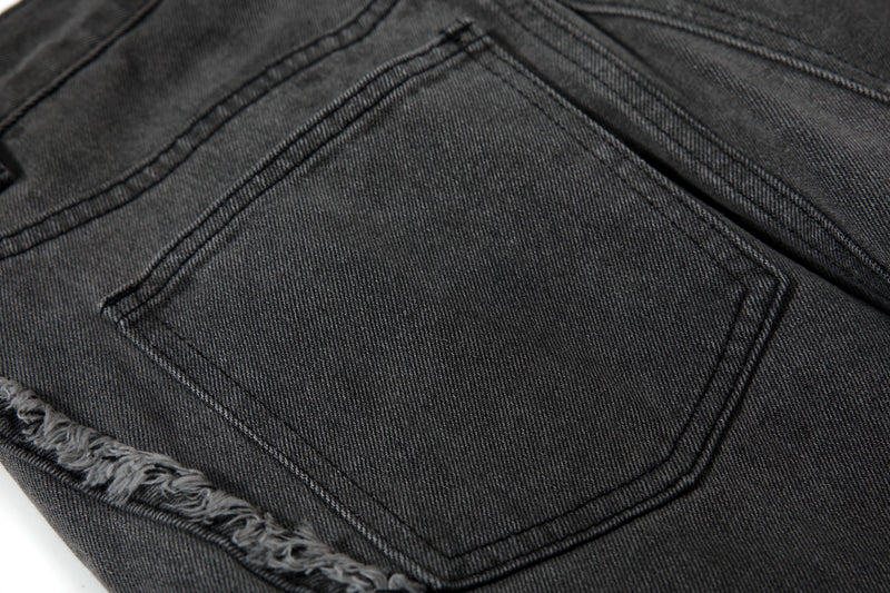 Close-up of back pocket and frayed seam detail on black cargo jeans