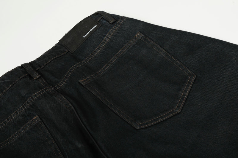 Close-up of black denim back pocket and waistband with stitched label at the top