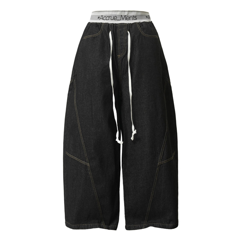 Front view of black wide-leg denim pants with white drawstring waist and oversized fit