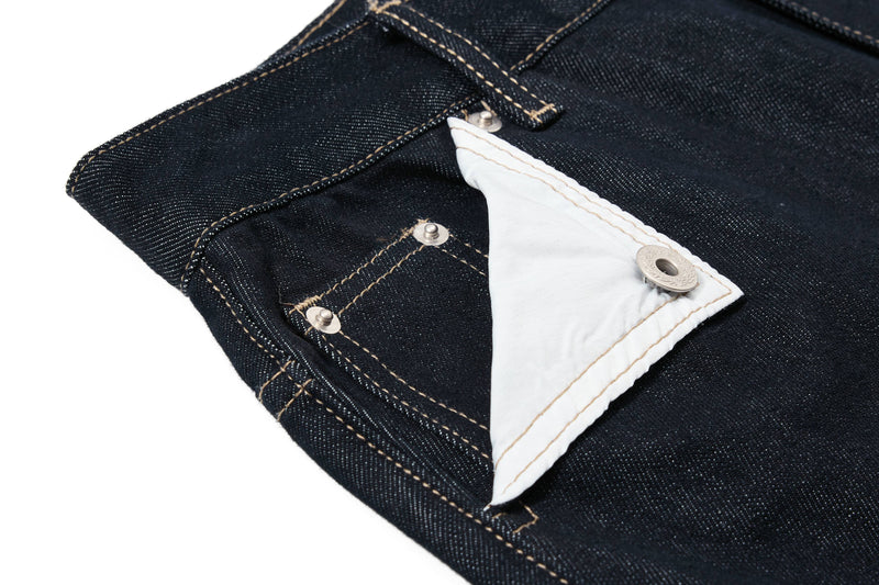 Close-up of a white contrast pocket flap on dark wash denim pants with metal snap hardware