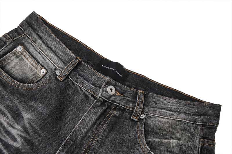 Close-up of front waistband on faded black jeans with button fly, belt loops, and pocket trim