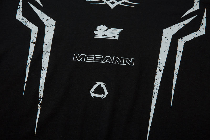 Close-up of black tee lower front with white Mccann text and circular icon
