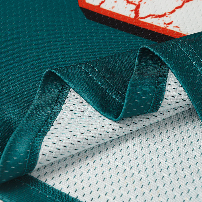 Close-up of a teal football jersey with white mesh lining and stitched hem for a streetwear sports tee look