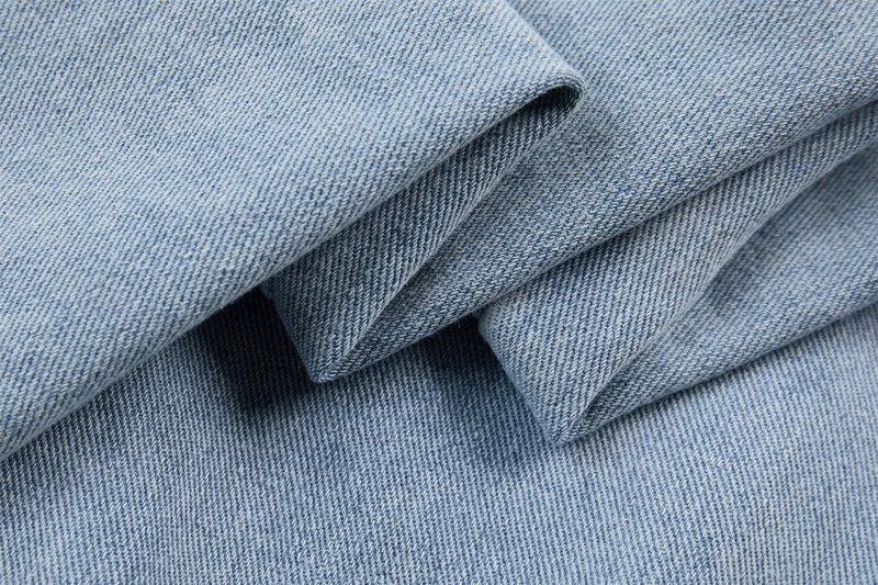 Close-up of light wash denim fabric folds showing soft twill texture