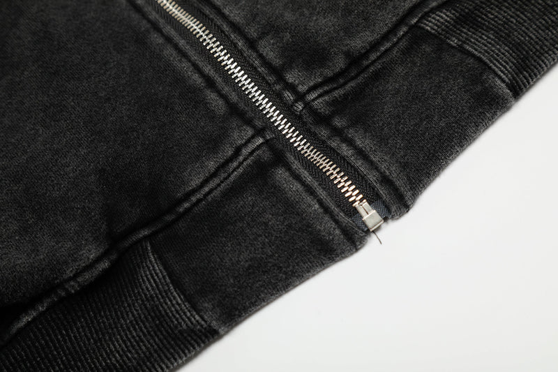Close-up of black hoodie jacket hem with diagonal zipper ending and ribbed trim