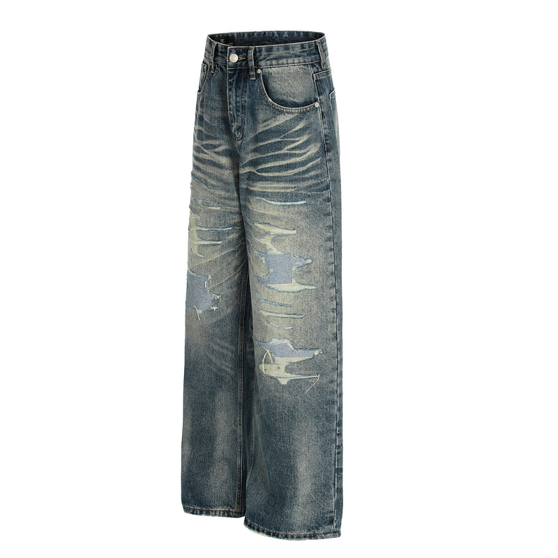 Angled front view of distressed blue wide-leg jeans with faded whiskering and ripped details