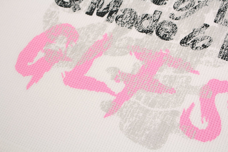Close-up of distressed pink and black graphic text on white waffle-knit streetwear tee fabric