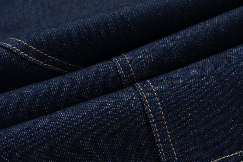 Close-up of folded raw indigo denim showing curved seam stitching and textured fabric
