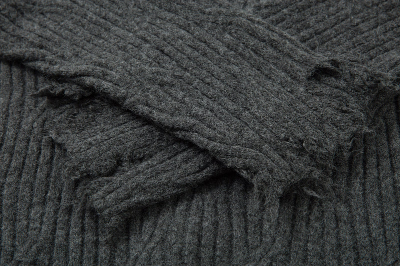 Close-up of charcoal gray knit fabric showing heavy distressing and loose threads