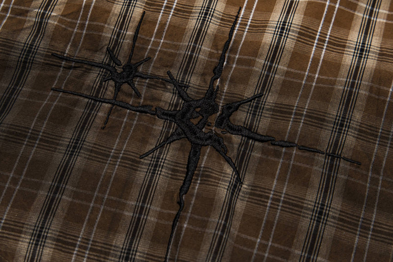 Brown plaid shirt with black abstract graphic embroidery, close-up of vintage retro streetwear fabric texture