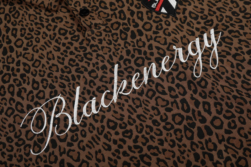 Leopard print polo shirt with white script embroidery and black button collar detail