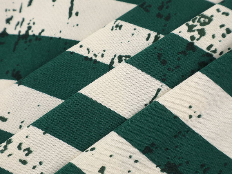 Close-up of green striped tee fabric with diagonal folds and distressed print