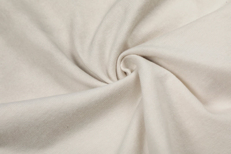 Close-up of cream cotton fabric with soft folds, showing the distressed vintage texture of a graphic band tee