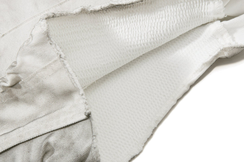 Close-up of the leg opening and inner seam on light gray denim shorts