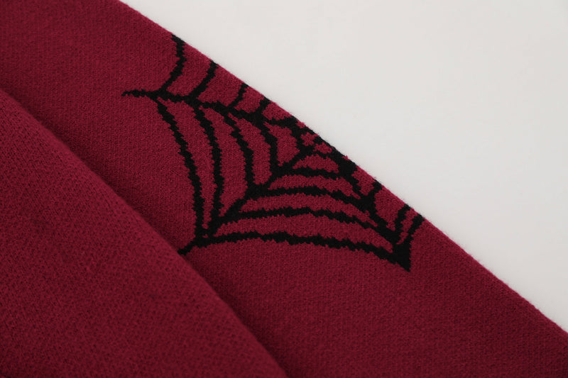 Close-up of burgundy sleeve with black spiderweb knit pattern on knitted hoodie