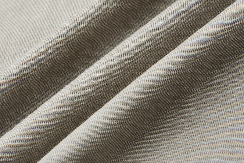 Close-up of vintage washed heavyweight cotton tee fabric with soft ribbed texture and muted beige tones