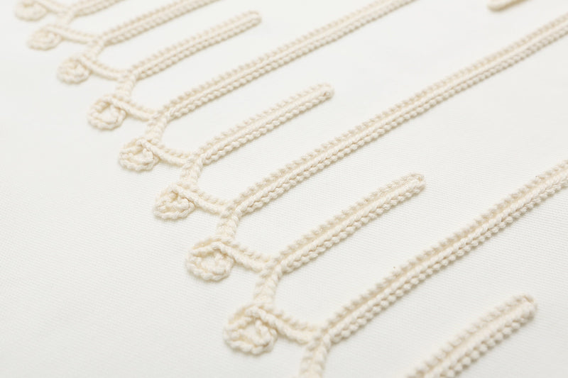 Close-up of cream rope embroidery and braid detailing on a white military-style polo shirt