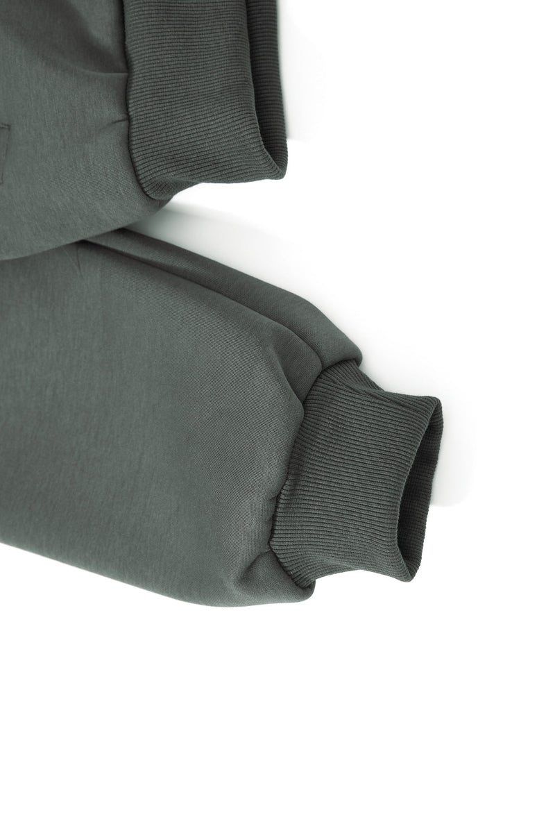 Close-up of ribbed cuff and sleeve hem on dark green hoodie