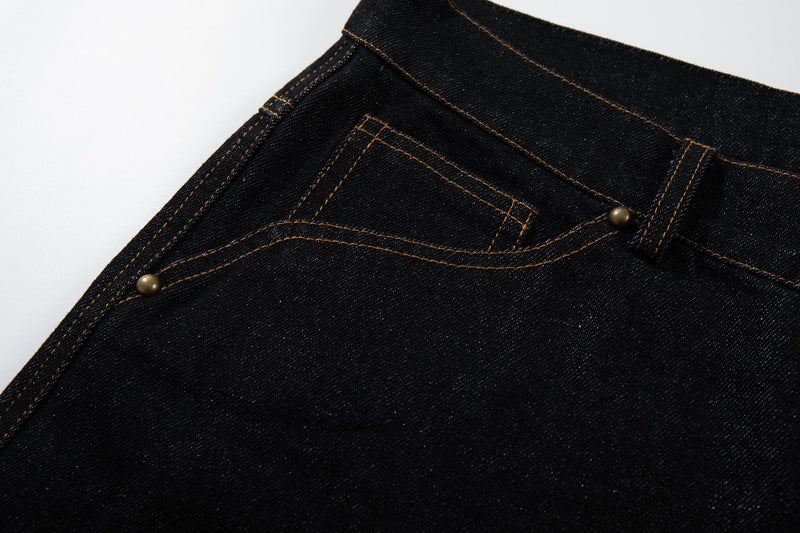 Close-up of the front pocket and curved seam detail on black denim pants