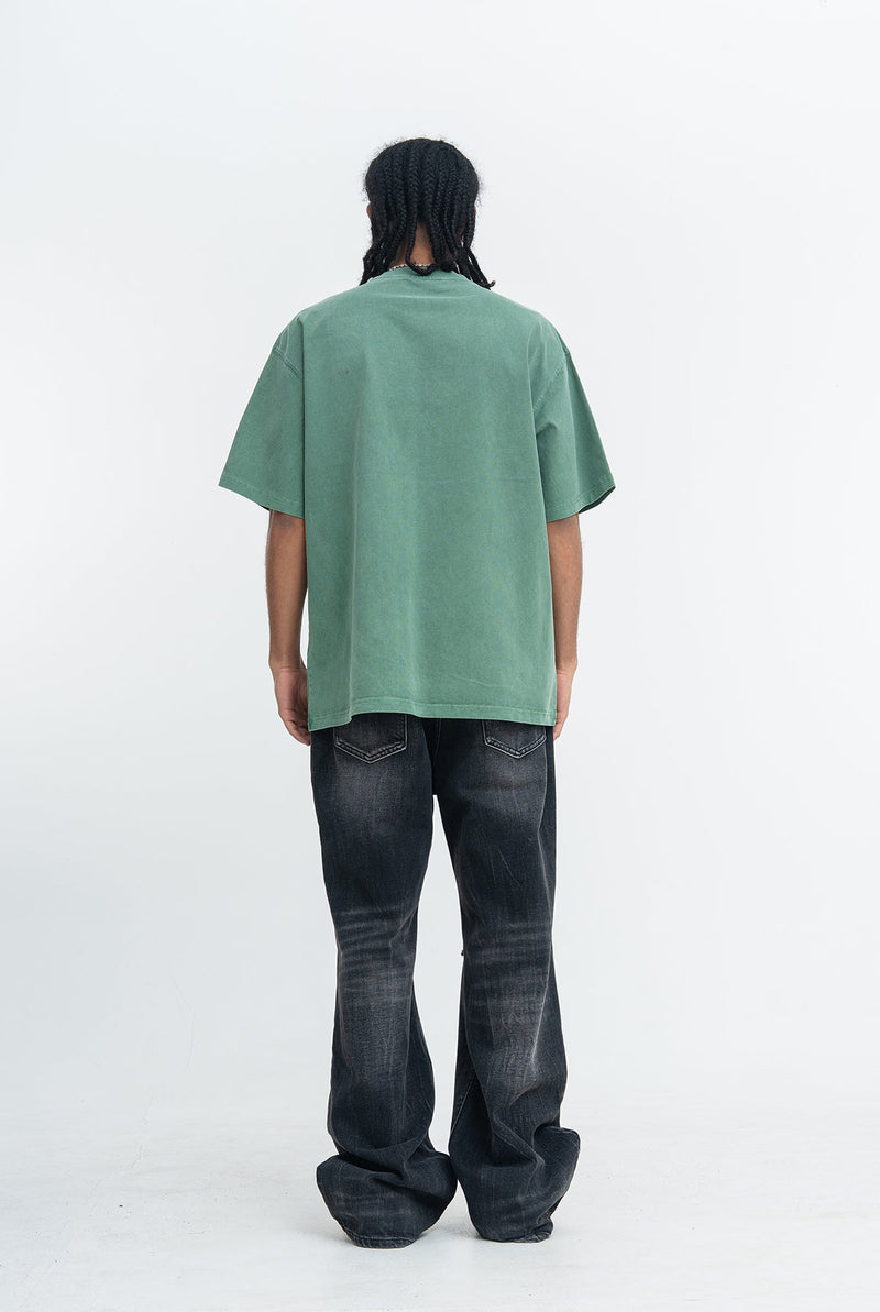 Back view of a vintage wash green graphic T-shirt paired with faded black jeans, streetwear style