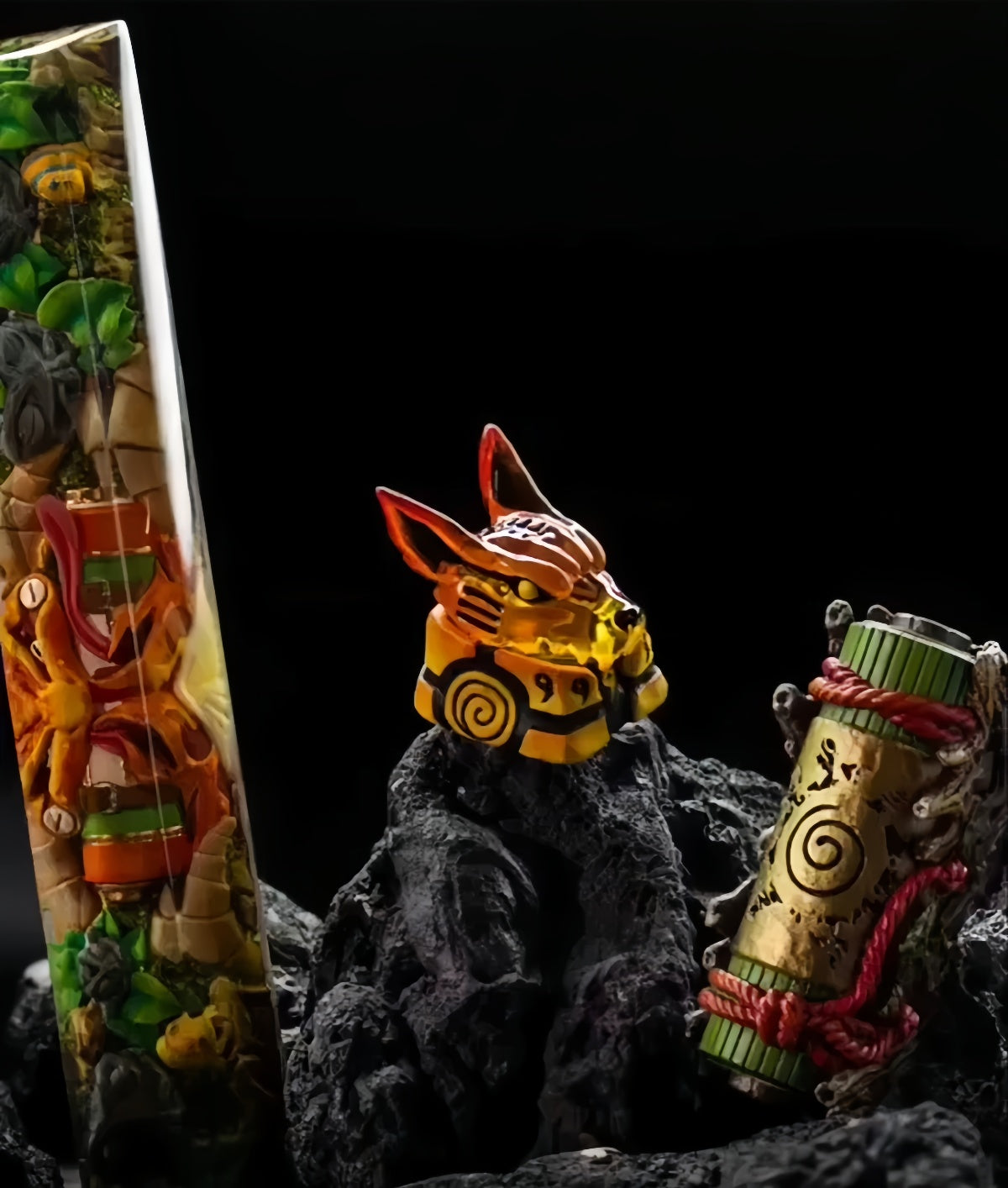 A collection of decorative items on black rocks includes the vibrant Naruto Ninja Keycaps Set, featuring designs like a vertical object with colorful patterns resembling a scroll, a fox-eared figurine with a yellow body representing Kurama and tailed beasts amidst the dark-themed setup.