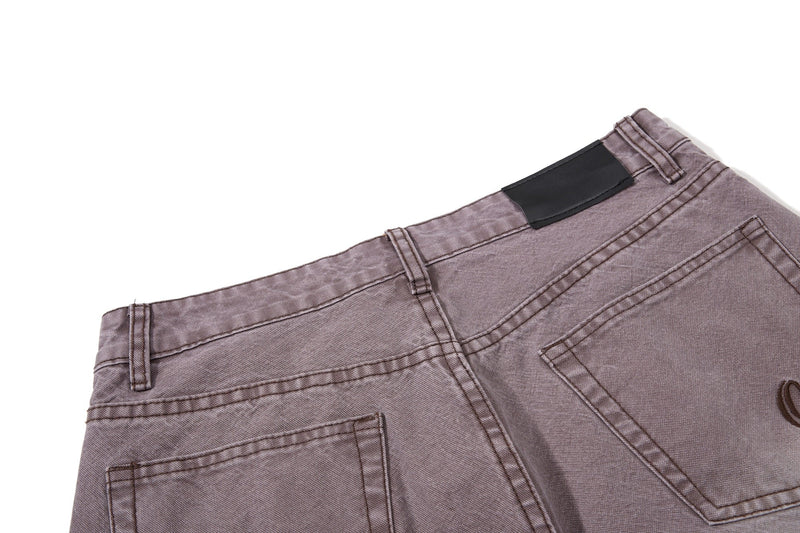 Close-up of brown denim back waistband with black patch detail