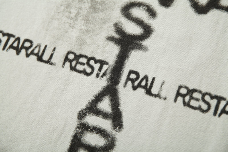 Close-up of a white distressed raglan tee with bold black graffiti-style text print and faded underground streetwear design