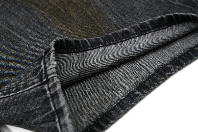 Close-up of folded denim hem showing heavy black wash and contrast stitching