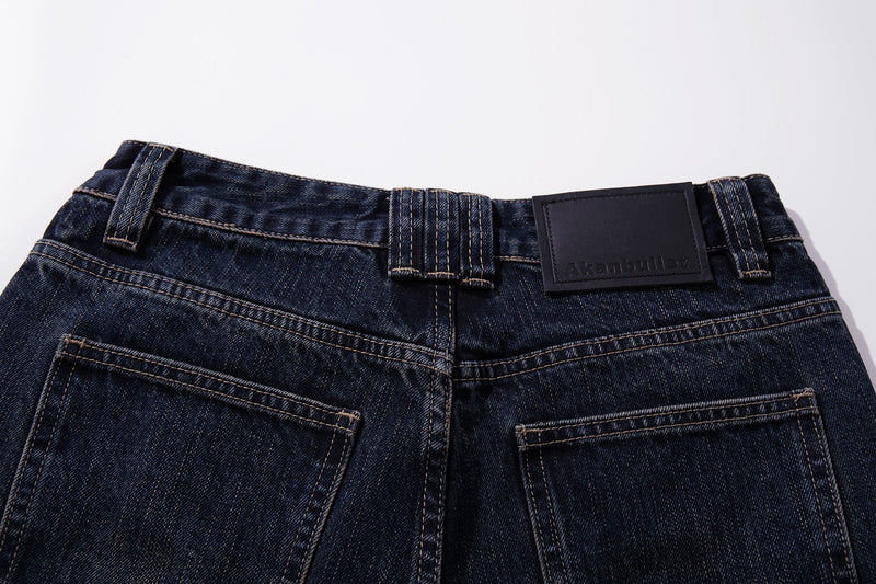 Close-up of the back waistband on dark wash jeans with belt loops and leather label
